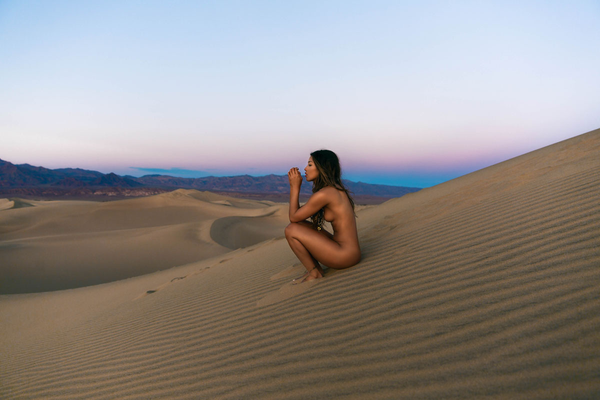 Грудастая брюнетка позирует в пустыне голышом на закате - порно фото